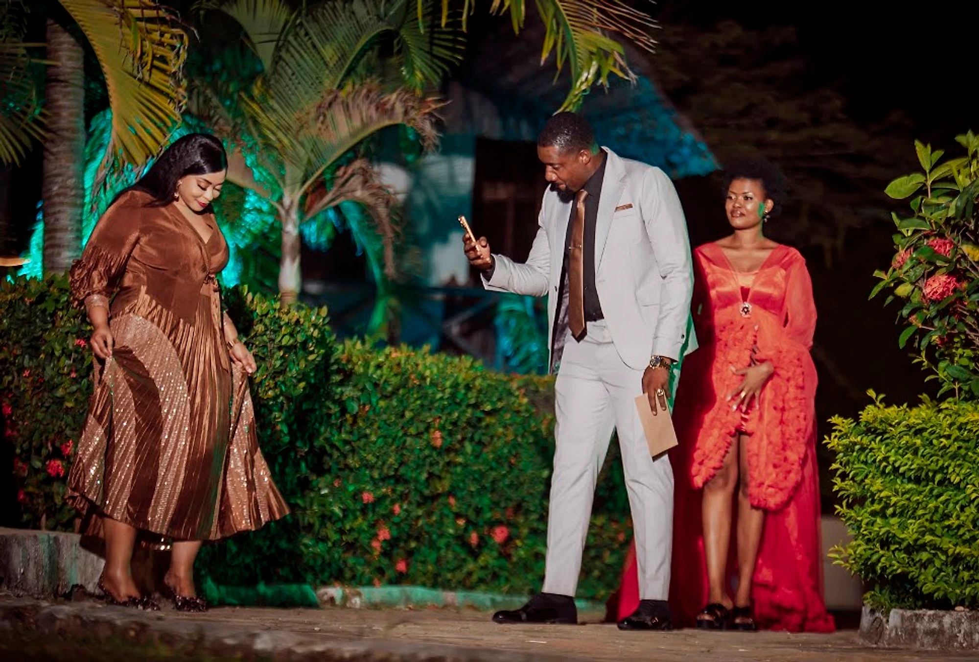 Three actors in a garden at night
